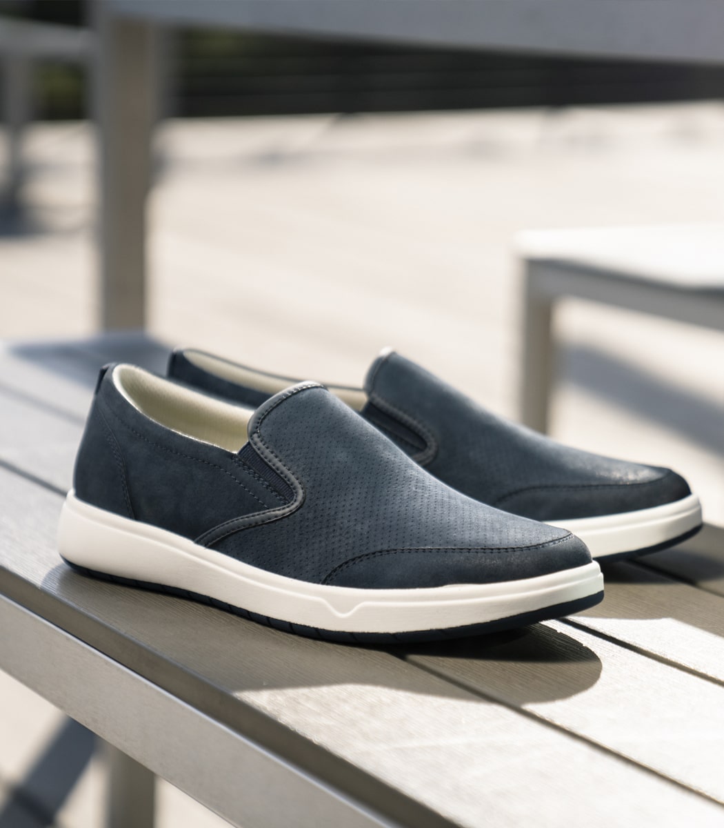 The featured product is the Premier Plain Toe Slip On Sneaker in Navy.