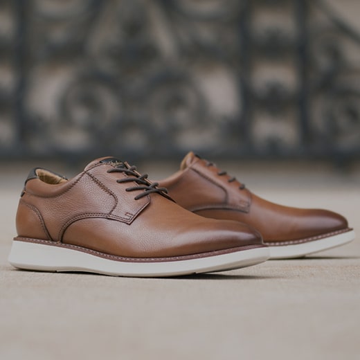 The image features a model walking up wooden steps while wearing brown Men’s hybrid shoes. Shop the Men’s Hybrid Shoes category now.
