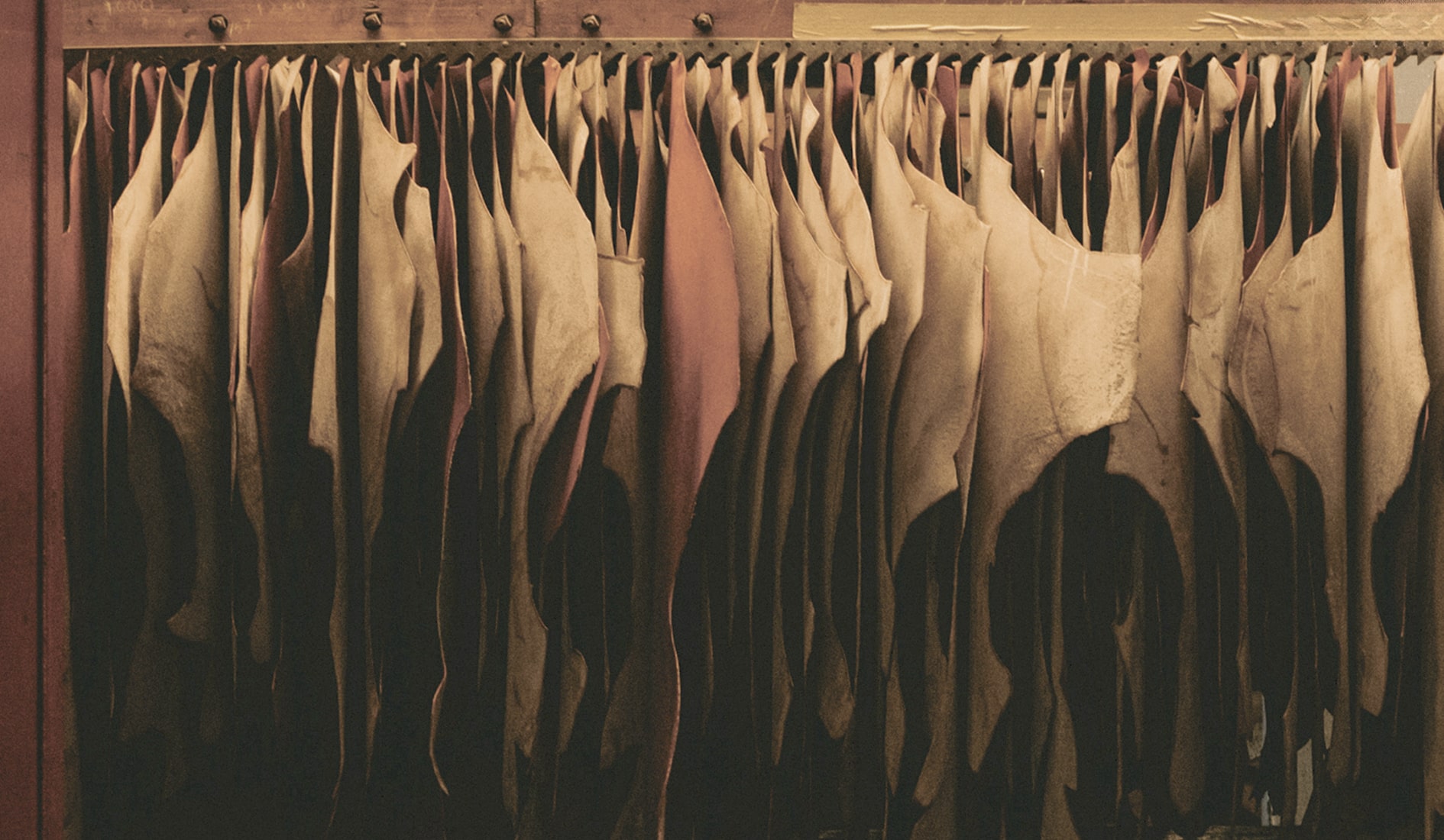 Image features pieces of leather hanging up.