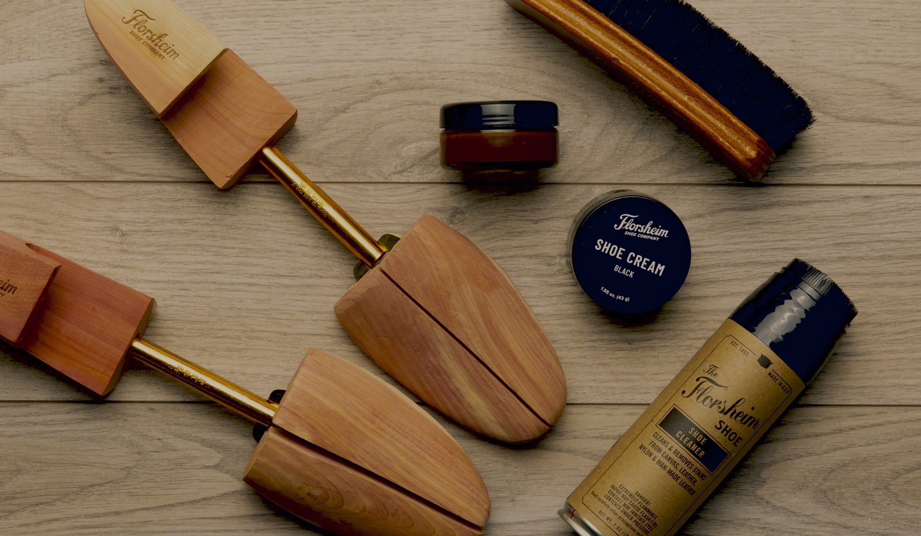 Image features a variety of shoe care tools on a wood background.