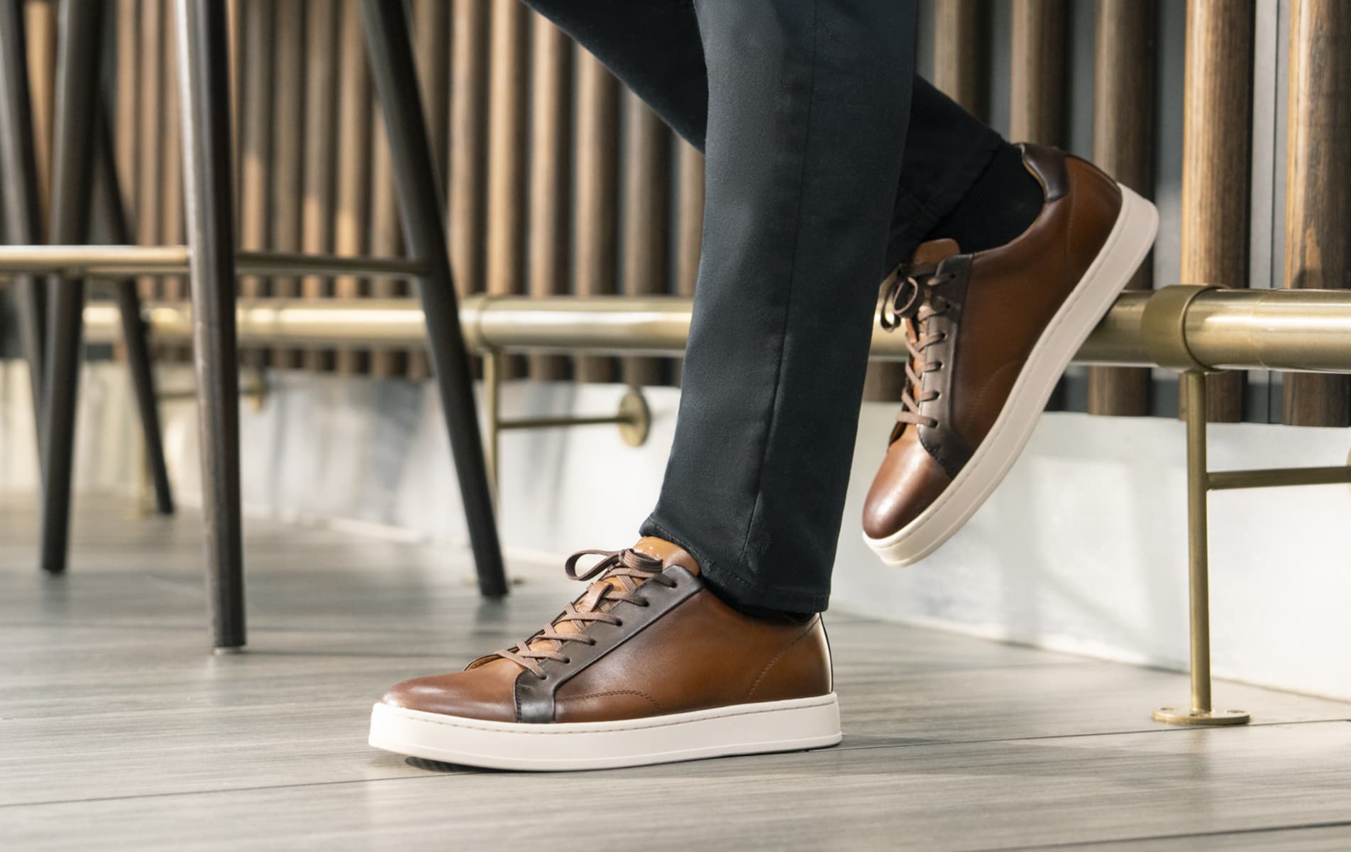 Shop Florsheim casuals featuring the Monopoli lace to toe sneaker in cognac leaning against a bar. 
