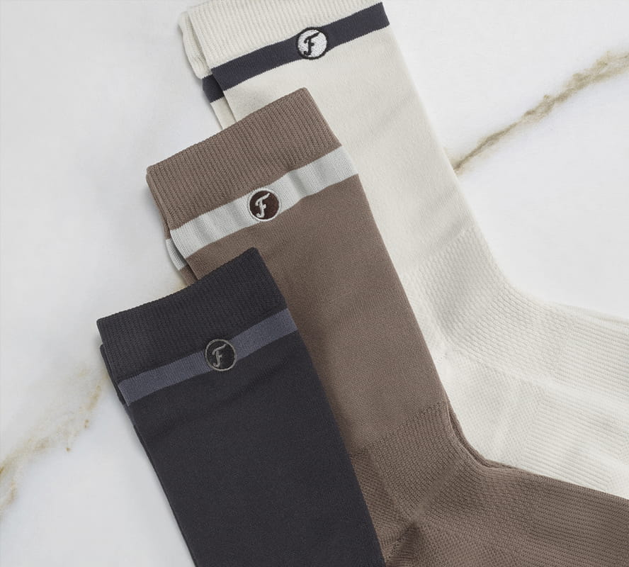 Shop Florsheim accessories featuring a variety of socks on a white marble background.