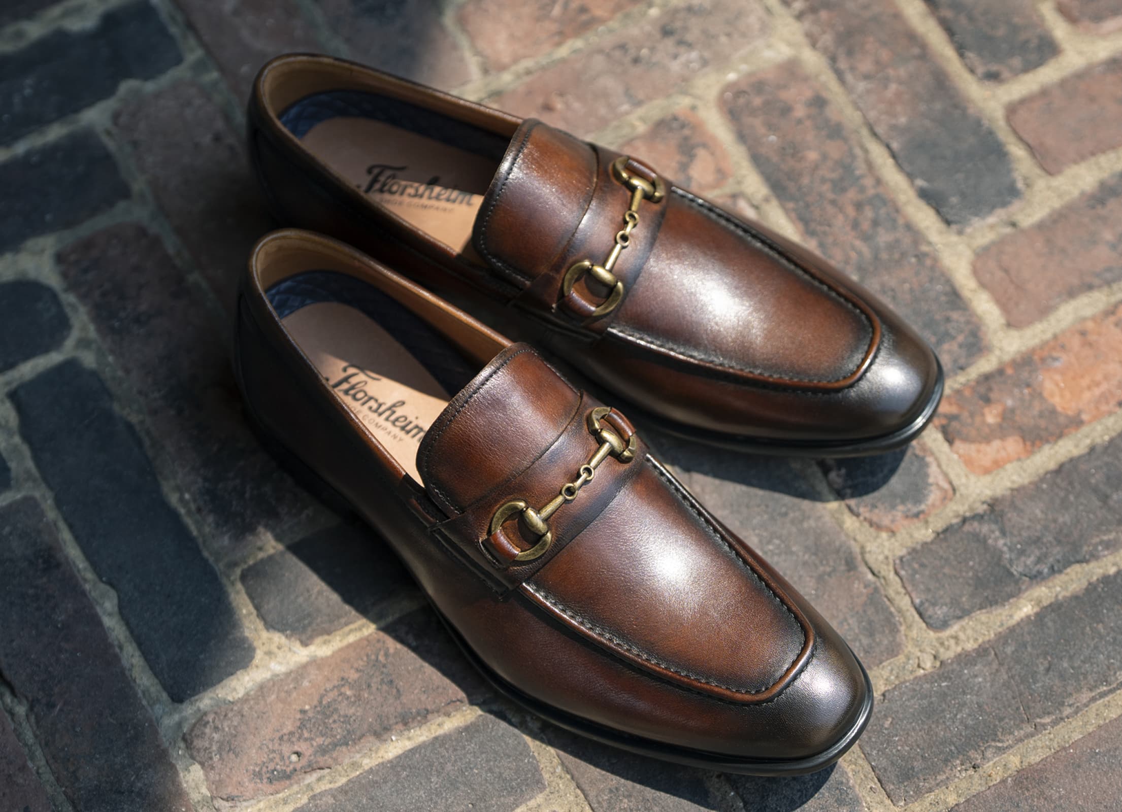 Shop Florsheim new arrivals featuring the Zaffiro Bit Loafer II in brown on a brick background.