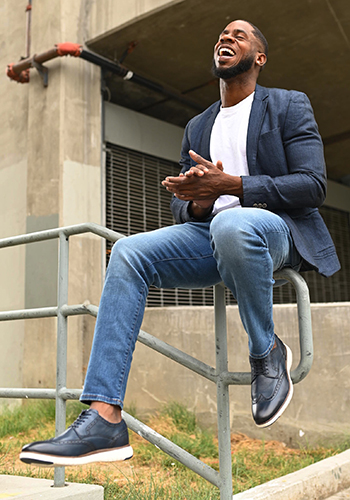 Image of social media influencer Chidi Ezemma sitting and laughing in the Flair Wingtip Oxford in Navy.