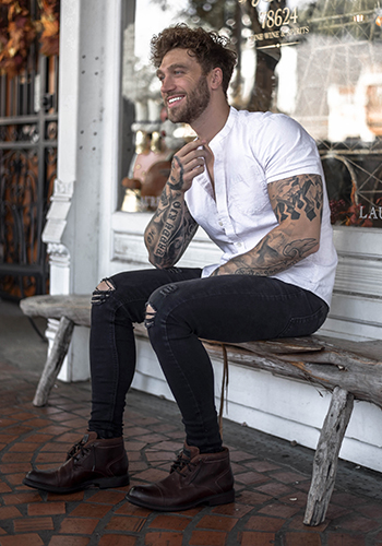 Image of social media influencer Jean-Edouard Grimoult sitting on a bench wearing the Vandall Cap Toe Lace Up Boot in Cognac.