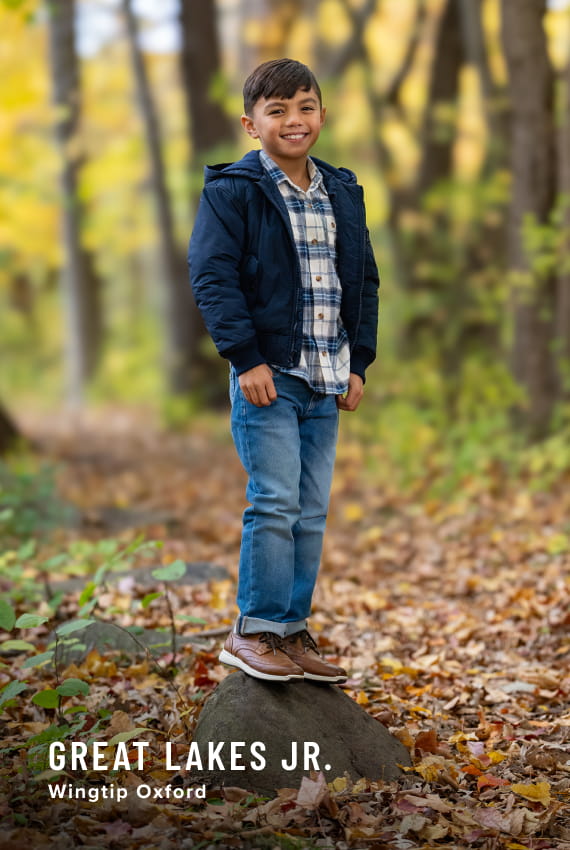 Kids Shoes view all category. Image features a child wearing the Great Lakes Junior Wingtip Oxford in a forest setting.