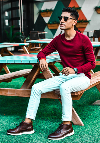 Image of social media influencer Hector Benavides sitting outside on a picnic bench wearing the Flair Plain Toe Chukka Boot in Brown.