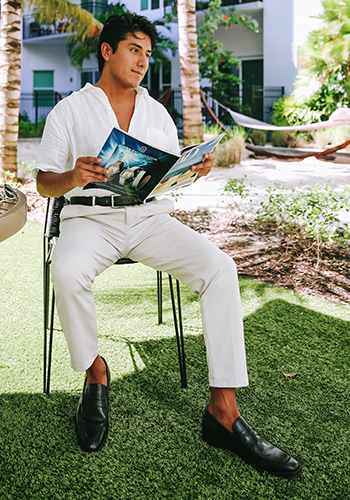 Image of social media influencer Marco Arrieta sitting outside in Florida wearing the Sorrento Moc Toe Penny Loafer in Black.