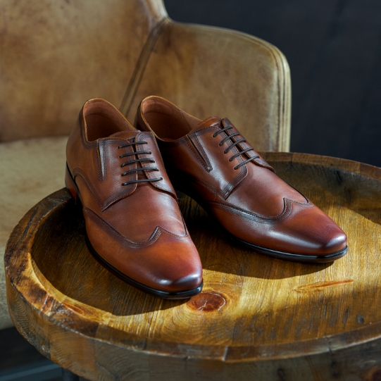 "Keeping Up With Men’s Shoe Fashion Trends As The Seasons Change." The featured product is the Postino Wingtip Oxford in Cognac.