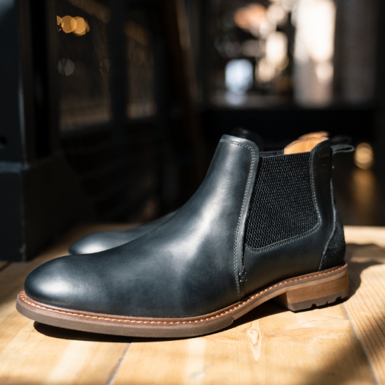"Elevate Your Style With A Pair Of Men’s Black Boots."  The featured product is the Lodge Plain Toe Gore Boot in Black Crazy Horse.