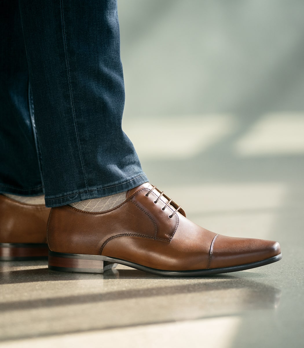 The featured image is a model wearing the Postino Cap Toe Balmoral Oxford in Cognac Smooth. 