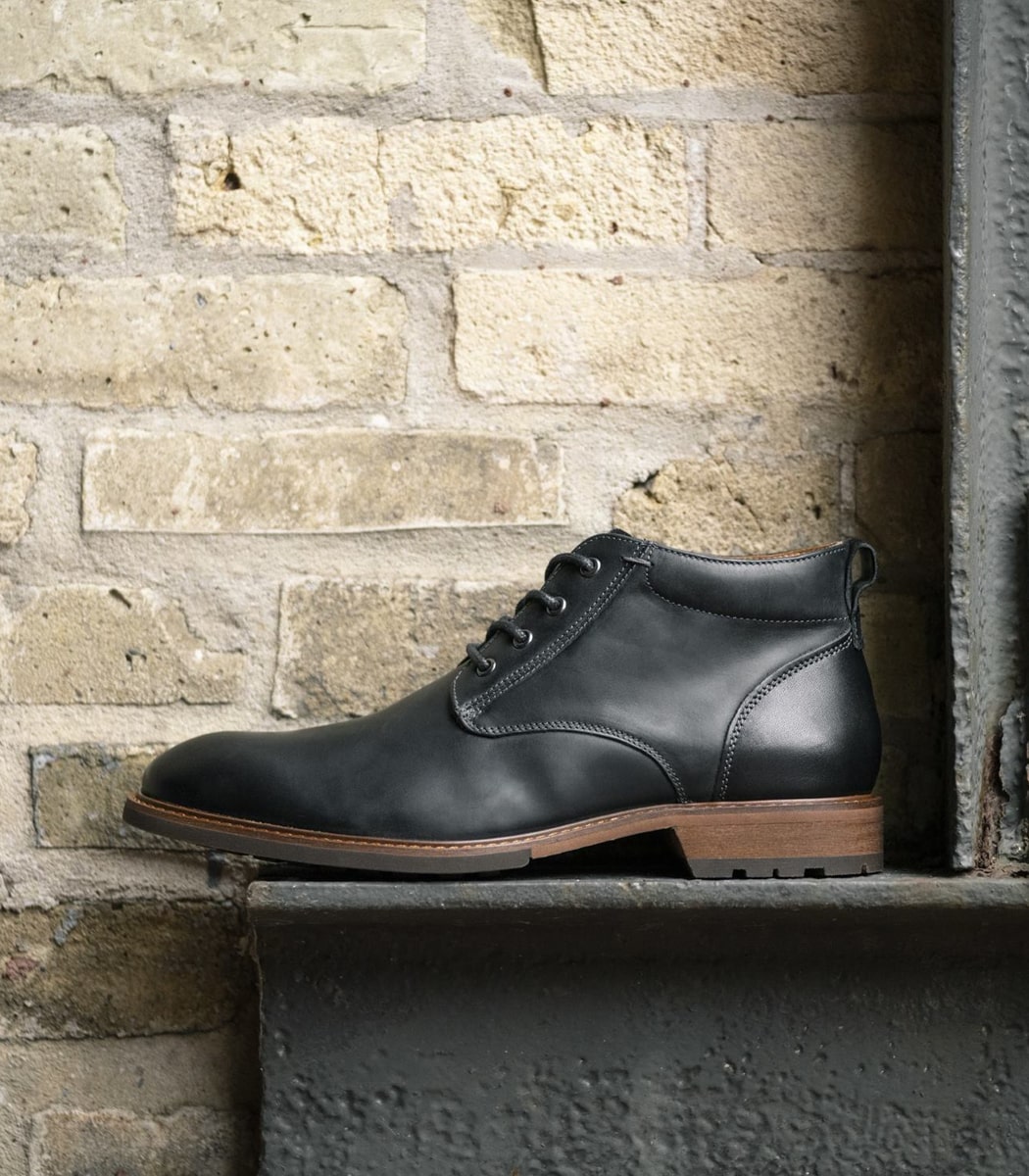 The featured shoe is the Lodge Plain Toe Chukka Boot in Black Crazy Horse.