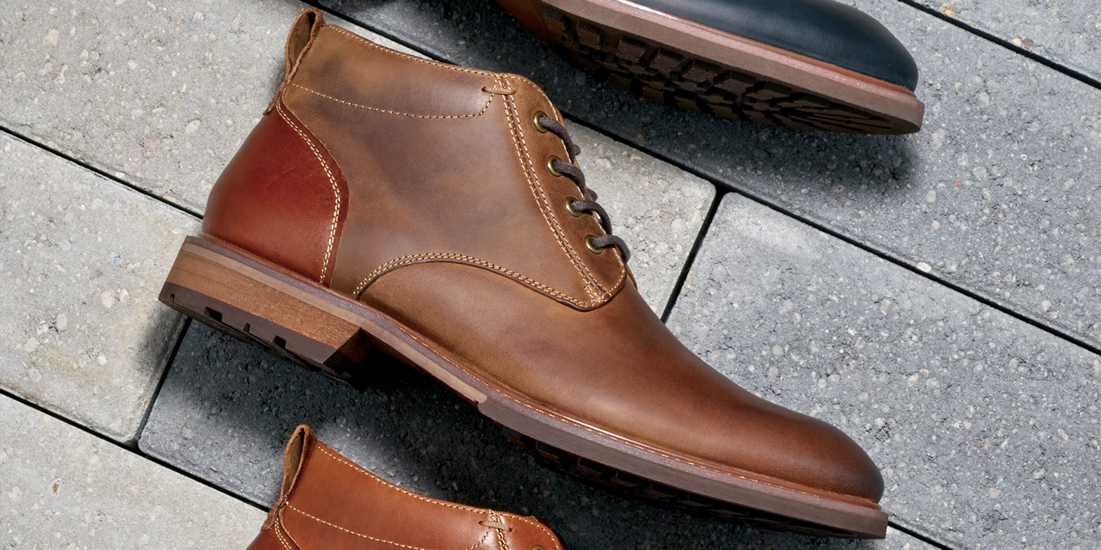 The featured image is the Lodge Plain Toe Chukka Boot in Brown Crazy Horse lying on cobblestones.